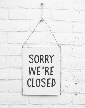 White square metal plate on white bricks background - with text sorry we're closed - not open - mock up - template