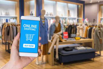 Adult hand holding smartphone with online shopping application screen on blurred of shopping mall...