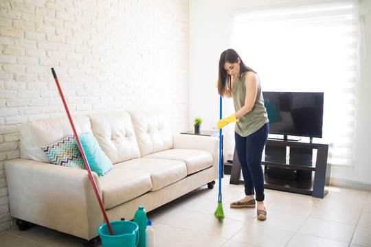 Young woman busy sweeping floor