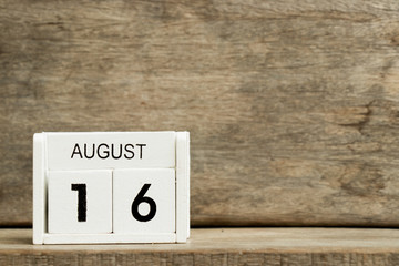 White block calendar present date 16 and month August on wood background