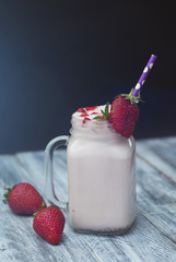 Milk Cocktail Shake Drink with Srawberry. homemade Fruit Milkshake with Straw in Glass. Rustic Gray wooden Background.