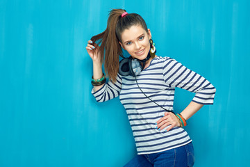 Smiling happy teenager girl portrait on blue wall background.