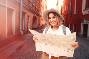 Travel guide. Young female traveler with backpack and with map on the street. Travel concept