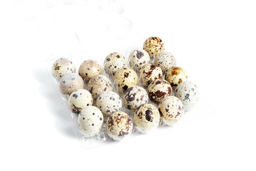 Obraz premium Quail spotted eggs in a transparent plastic container on white background