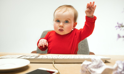 Happy child baby girl toddler sitting with keyboard of computer isolated on a white background