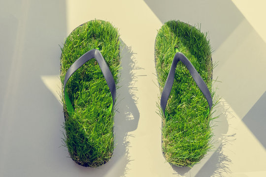 Footprint, sandals made of green artifitial grass on marble background. Save the nature, environment, ecology concept