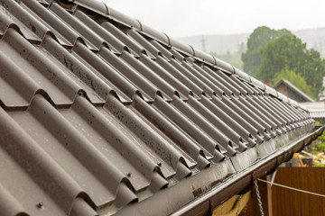 Roof with brown tiles under the rain