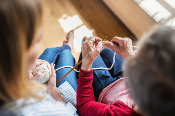Obraz premium An unrecognizable elderly grandmother and adult granddaughter at home, knitting.