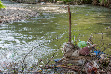 Human garbage in small creek on focus,  poluting the environment.