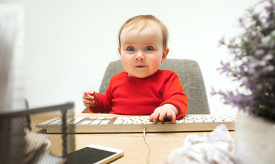 Happy child baby girl toddler sitting with keyboard of computer isolated on a white background