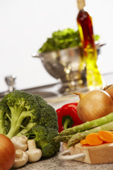 FRESH LETTUCE BROCOLLI CARROTS ASPARAGUS RED PEPERS ONIONS AND OLIVE OIL ON KITCHEN WORKTOP