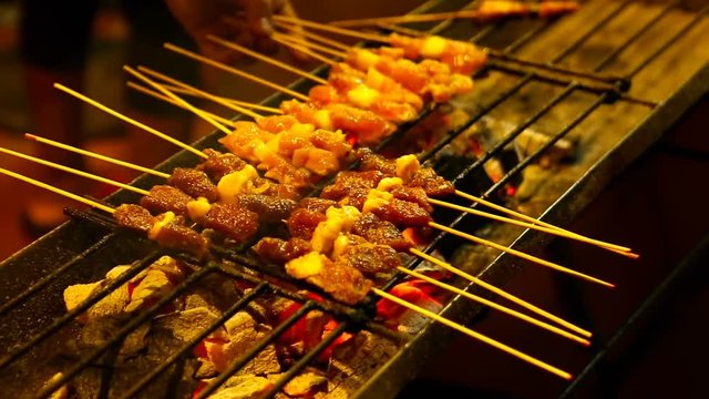 Meat to grill on charcoal. People cooking, selling and buying Asian street Food.