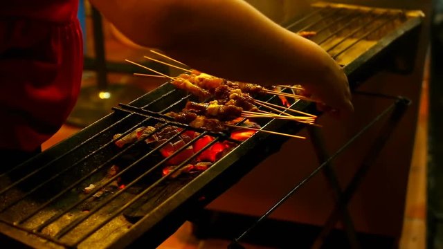 Meat to grill on charcoal. People cooking, selling and buying Asian street Food.