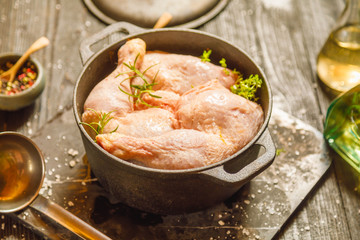Raw chicken or turkey legs with solt and pepper in old clay dish on a black wooden rustic background. Copy space