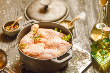 Raw chicken or turkey legs with solt and pepper in old clay dish on a black wooden rustic background. Copy space