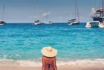Fototapeta na wymiar Young beautiful woman in swimsuit and hat relaxing on Navagio beach, Zakynthos island, Greece