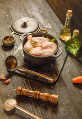 Raw chicken or turkey legs with solt and pepper in old clay dish on a black wooden rustic background. Copy space