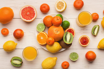 Platter of assorted citrus fruits on white wooden planks, top view