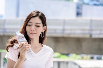 Fototapeta premium Asian beautiful woman has water drinking with city background in the morning.