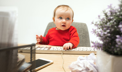 Happy child baby girl toddler sitting with keyboard of computer isolated on a white background