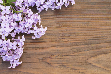 Fototapeta na wymiar Fresh flowers frame of purple Lilac flowers on wooden background
