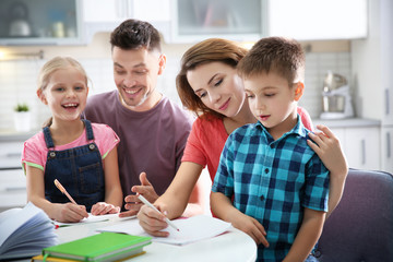 Little children with parents doing homework at home