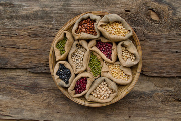 various legumes in wooden basket on wooden background