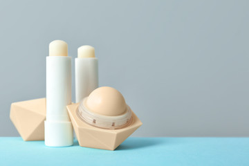 Hygienic lipsticks and balms on table against grey background