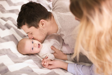 Young parents with baby on bed at home