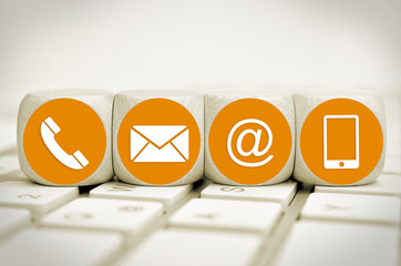 Website and Internet contact us page concept with orange icons on cubes on a keyboard
