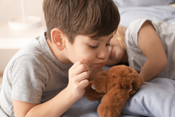 Cute children with toy on bed at home