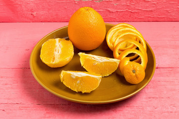 orange Spiral peel half slice on dish on pink wood
