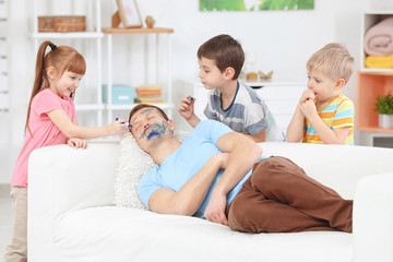 Little children painting their father's face while he sleeping. April fool's day prank