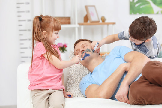 Little children painting their father's face while he sleeping. April fool's day prank