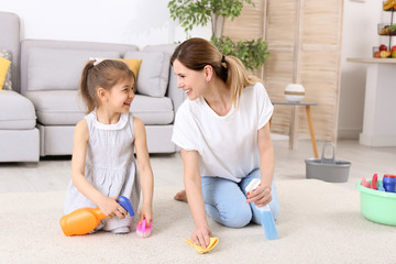 Housewife with daughter cleaning carpet in room together