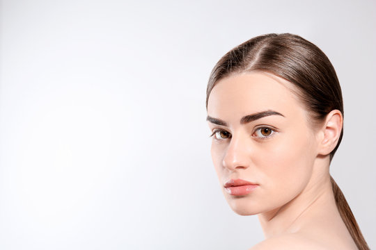 Beautiful woman with perfect eyebrows on light background