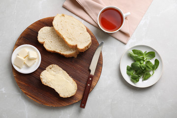 Flat lay composition with bread, butter and cup of tea on light background