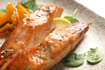 Tasty cooked salmon with lemon on plate, closeup