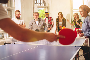Group of happy young friends playing ping pong table tennis