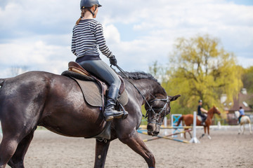 Young girl riding horse on her course in training show jumping. Equestrian sport training background