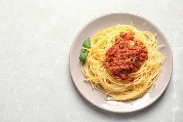 Plate with delicious pasta bolognese on light background, top view