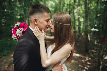 Beautiful young wedding couple is kissing and smiling in the park