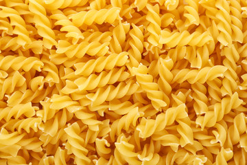 Uncooked fusilli pasta as background, closeup