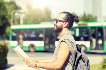 travel, tourism, backpacking and people concept - man traveling with backpack and map in city...