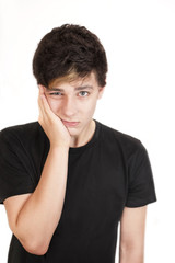 The guy holds his cheek and pity for a toothache on a white background. Vertical portrait of a teenager with toothache