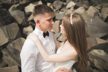 Gorgeous bride, groom kissing and hugging near the cliffs with stunning views