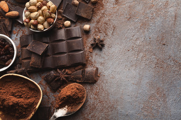 Crushed chocolate bar pieces and cocoa on gray background