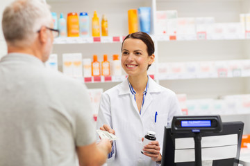 medicine, pharmaceutics, health care and people concept - apothecary and senior man customer buying...