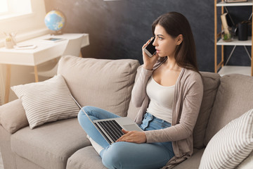 Girl at home working on laptop and talking on mobile