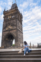 Woman with a dog in front of the tower of Charles Bridge